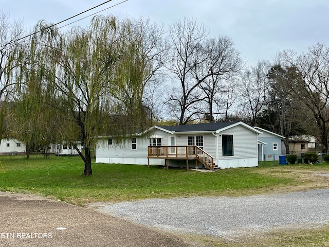 manufactured / mobile home featuring a front yard and a wooden deck