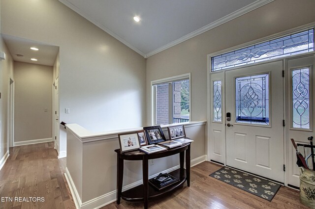 entryway featuring hardwood / wood-style floors, lofted ceiling, and crown molding