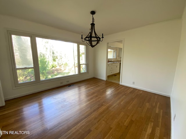 unfurnished dining area featuring hardwood / wood-style flooring and a chandelier