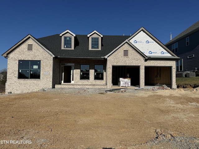 view of front of property with a garage, brick siding, and central air condition unit