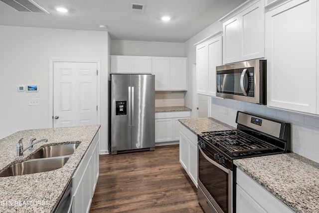 kitchen featuring stainless steel appliances, light stone counters, dark wood-type flooring, and sink