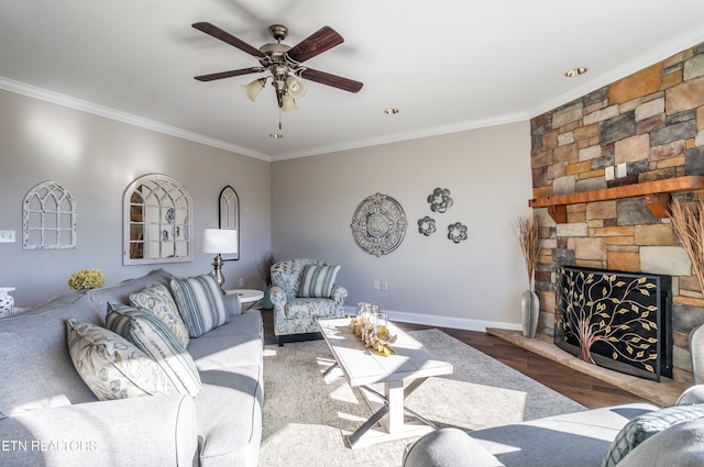 living room featuring dark wood-type flooring, a stone fireplace, ceiling fan, and ornamental molding