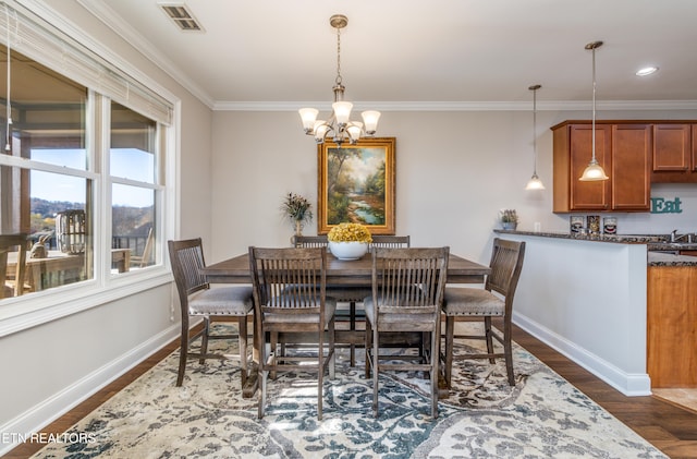 dining area featuring dark hardwood / wood-style flooring, crown molding, a notable chandelier, and sink