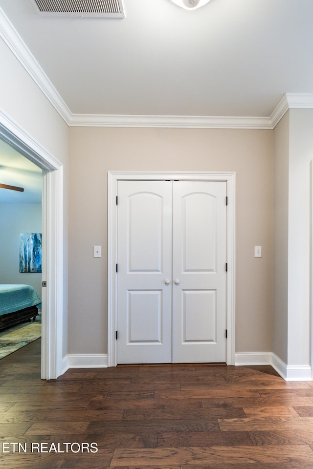 unfurnished bedroom featuring ornamental molding, dark wood-type flooring, and a closet