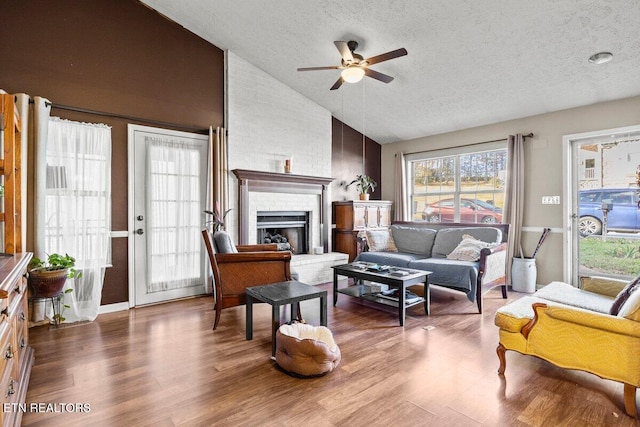 living room with hardwood / wood-style flooring, ceiling fan, a textured ceiling, and high vaulted ceiling