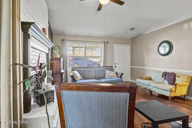 living room featuring wood-type flooring, a textured ceiling, and ceiling fan