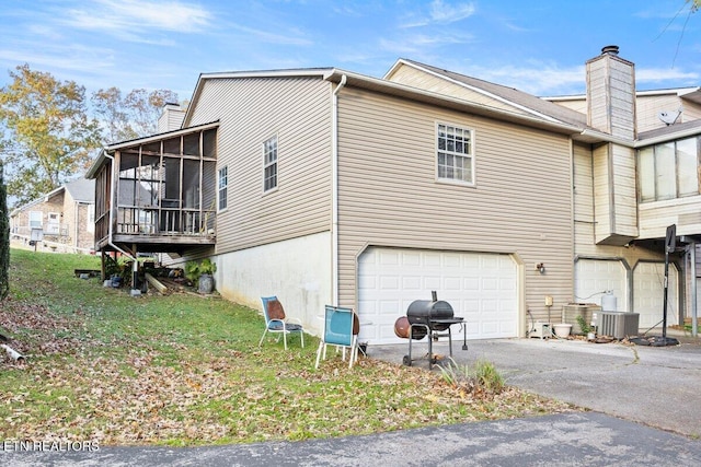 exterior space featuring a sunroom, a garage, and central air condition unit