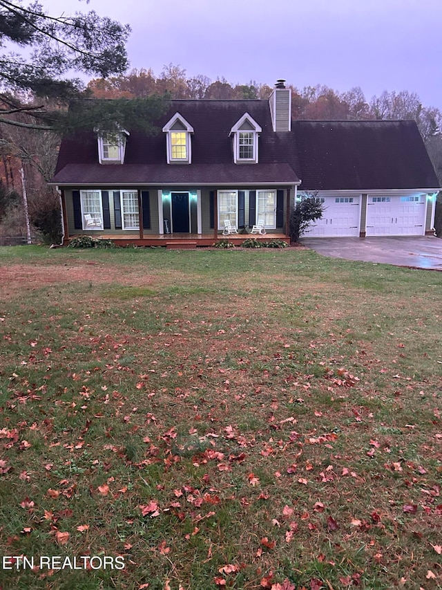 cape cod-style house featuring a garage and a front yard