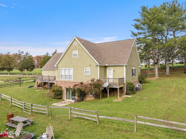 back of house featuring a rural view, a yard, and a wooden deck