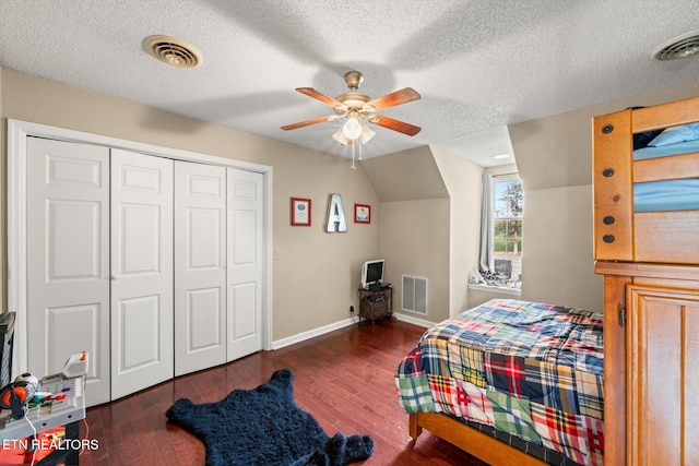 bedroom with ceiling fan, a closet, dark wood-type flooring, and a textured ceiling