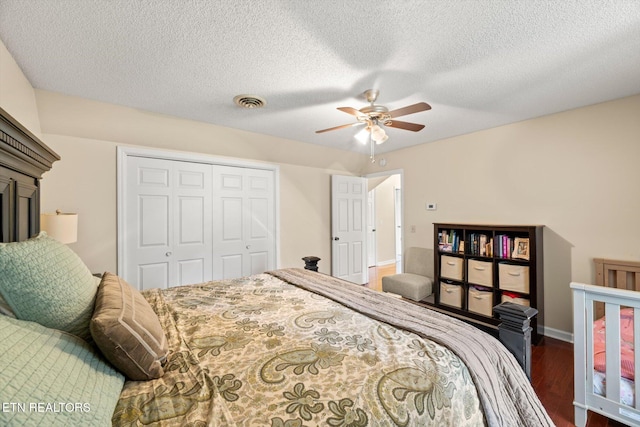 bedroom with ceiling fan, a closet, dark wood-type flooring, and a textured ceiling