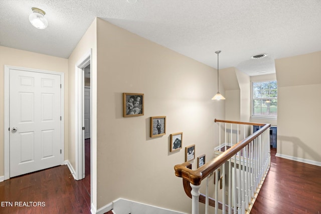 hallway featuring a textured ceiling and dark hardwood / wood-style floors