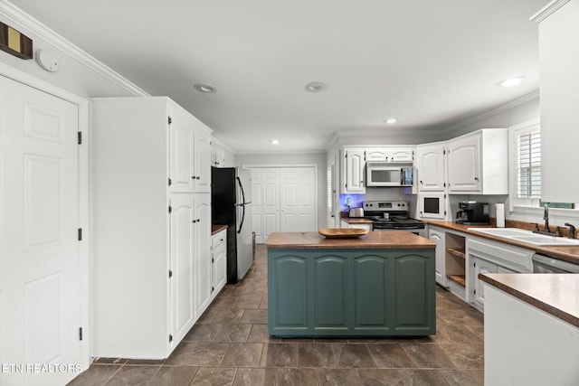 kitchen with a center island, white cabinets, sink, ornamental molding, and appliances with stainless steel finishes