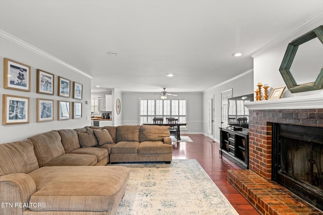 living room featuring dark hardwood / wood-style flooring, a brick fireplace, ceiling fan, and crown molding