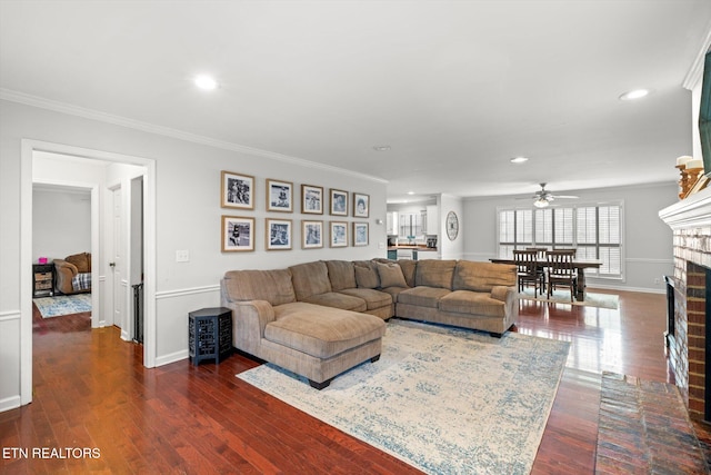 living room featuring crown molding, a fireplace, ceiling fan, and dark wood-type flooring