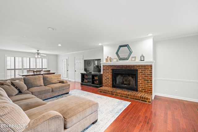 living room with hardwood / wood-style flooring, ceiling fan, crown molding, and a fireplace