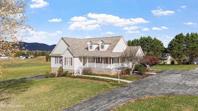 view of front of house featuring a mountain view, a porch, and a front lawn