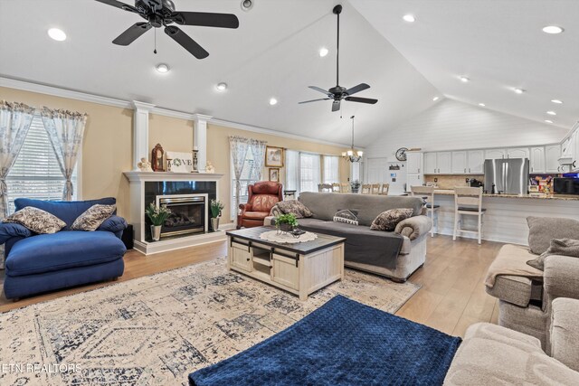 living room featuring plenty of natural light, ornamental molding, vaulted ceiling, and light wood-type flooring