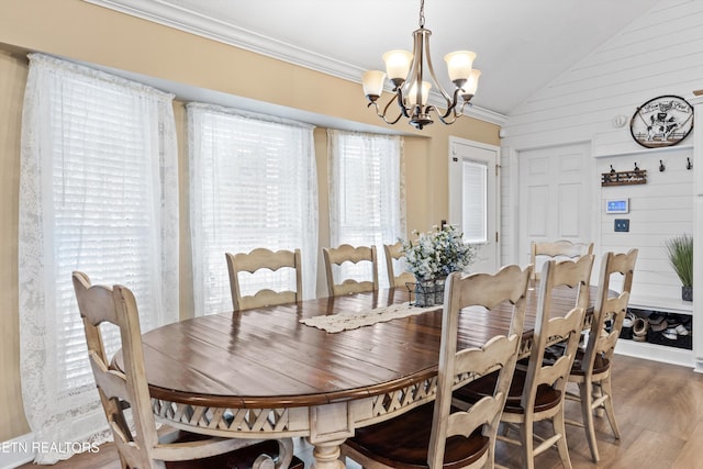 dining area with a chandelier, hardwood / wood-style flooring, vaulted ceiling, and wooden walls
