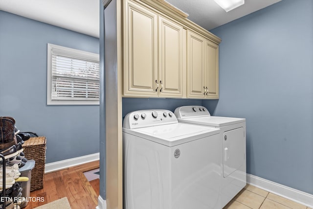 clothes washing area with cabinets, separate washer and dryer, and light hardwood / wood-style flooring