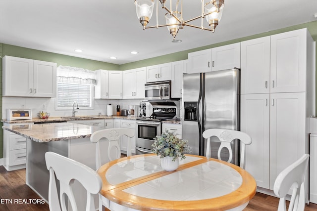 kitchen with dark hardwood / wood-style flooring, white cabinetry, hanging light fixtures, and stainless steel appliances