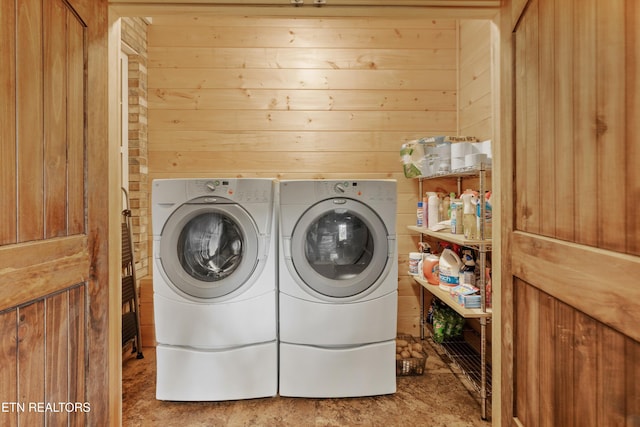 laundry area with wood walls and washing machine and dryer