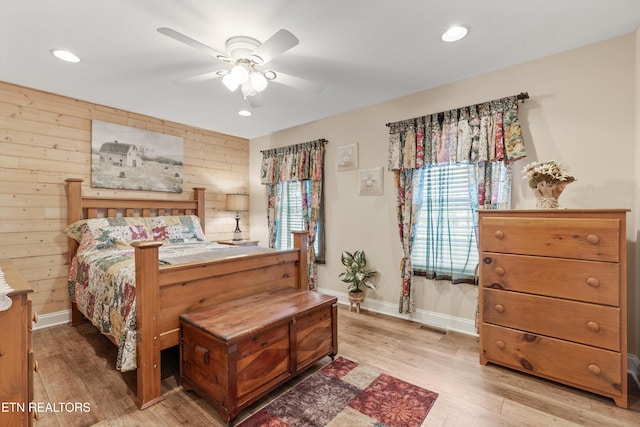 bedroom featuring wooden walls, ceiling fan, and light hardwood / wood-style floors