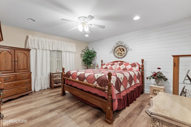 bedroom with light hardwood / wood-style flooring, ceiling fan, and wooden walls