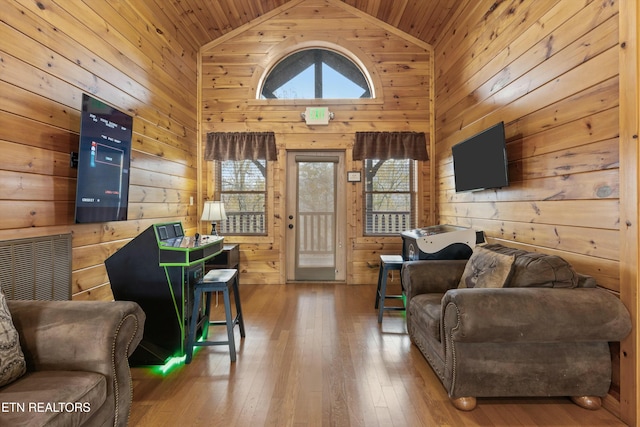 living room with a wealth of natural light, high vaulted ceiling, wood-type flooring, and wood walls