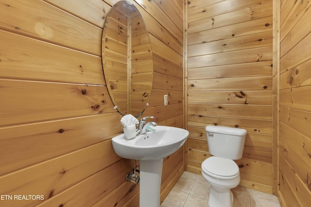 bathroom with tile patterned floors, toilet, and wooden walls