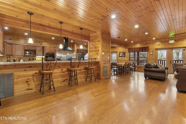 living room with french doors, light hardwood / wood-style floors, wooden ceiling, and wood walls