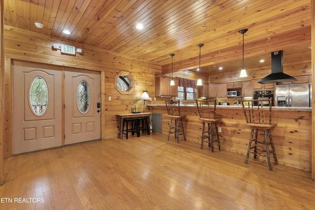 interior space with kitchen peninsula, island range hood, stainless steel appliances, and light wood-type flooring