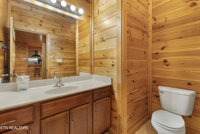 bathroom with tile patterned floors, vanity, toilet, and wooden walls