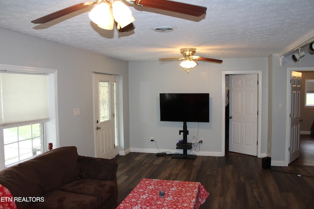 living room featuring ceiling fan, dark wood-type flooring, and a textured ceiling