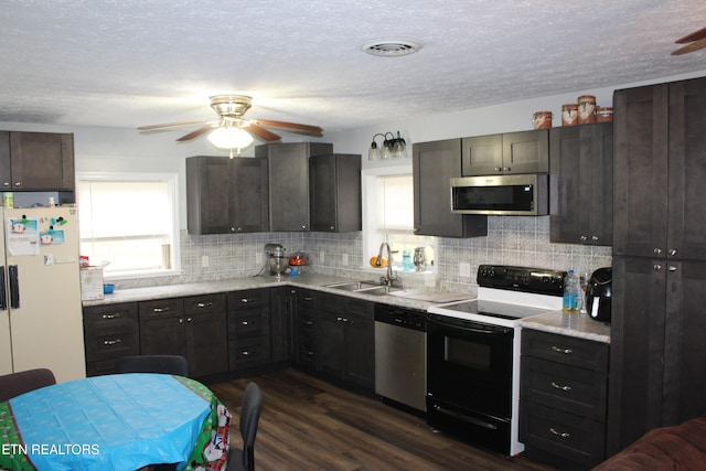 kitchen featuring appliances with stainless steel finishes, tasteful backsplash, ceiling fan, sink, and dark hardwood / wood-style floors