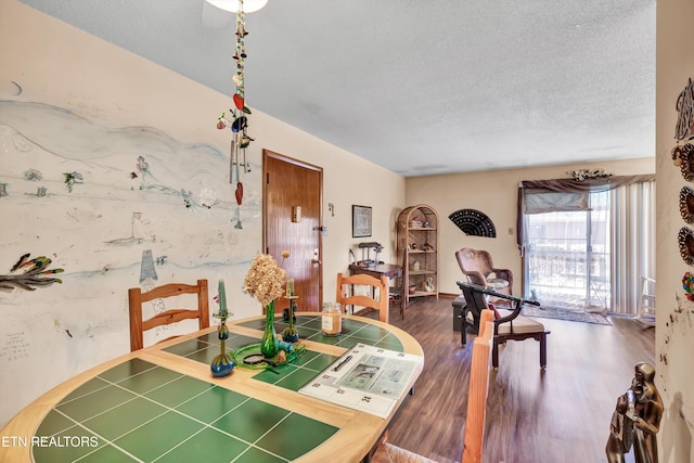 dining space featuring wood-type flooring and a textured ceiling