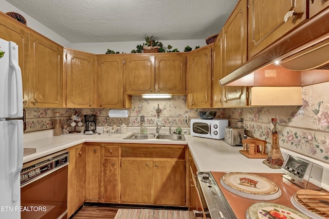 kitchen with a textured ceiling, sink, white appliances, and light hardwood / wood-style flooring