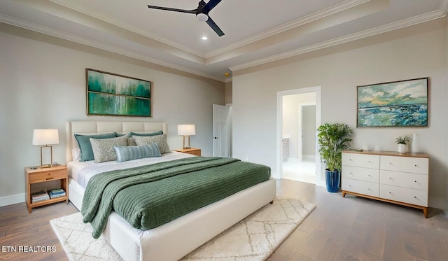 bedroom featuring a raised ceiling, wood finished floors, baseboards, ornamental molding, and recessed lighting