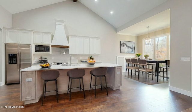 kitchen with black microwave, stainless steel fridge, a center island with sink, dark wood finished floors, and custom exhaust hood