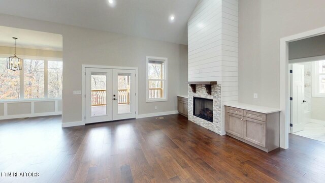 unfurnished living room featuring a large fireplace, dark wood-style flooring, and a healthy amount of sunlight
