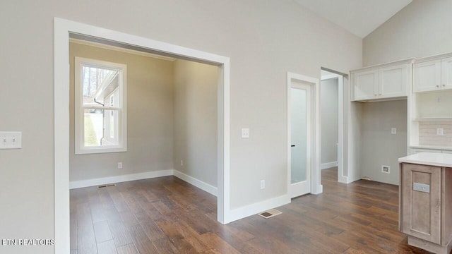 kitchen featuring white cabinetry, visible vents, lofted ceiling, and dark wood-type flooring