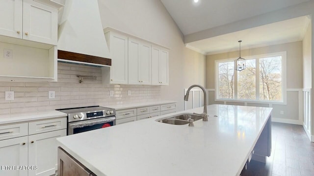 kitchen with vaulted ceiling, electric stove, a sink, a kitchen island with sink, and custom exhaust hood