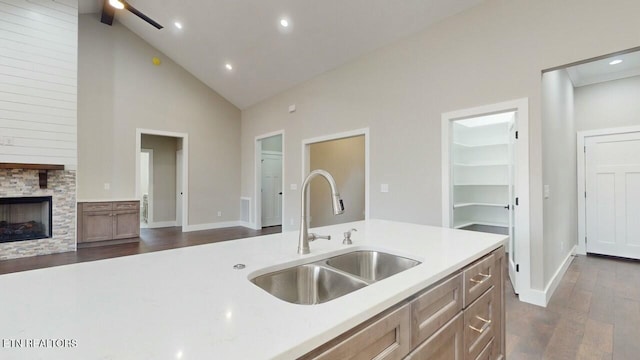 kitchen with a fireplace, light countertops, a sink, and dark wood-type flooring