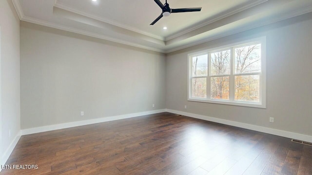 empty room with baseboards, dark wood-style flooring, a tray ceiling, and ceiling fan