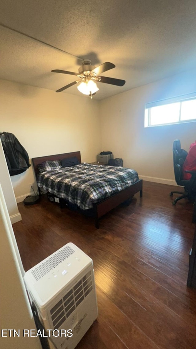 bedroom with a textured ceiling, ceiling fan, and dark wood-type flooring