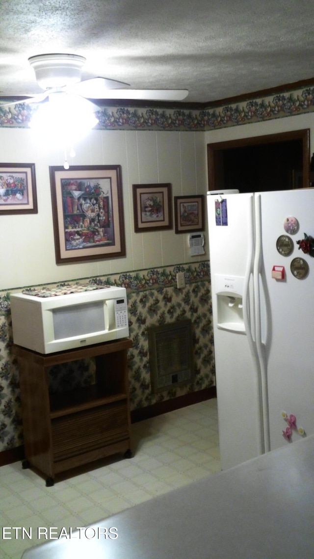 kitchen featuring a textured ceiling, heating unit, and white appliances