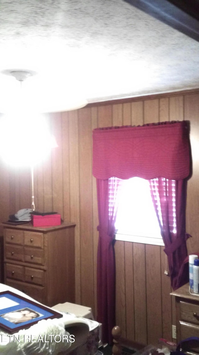 bedroom featuring wood walls and a textured ceiling