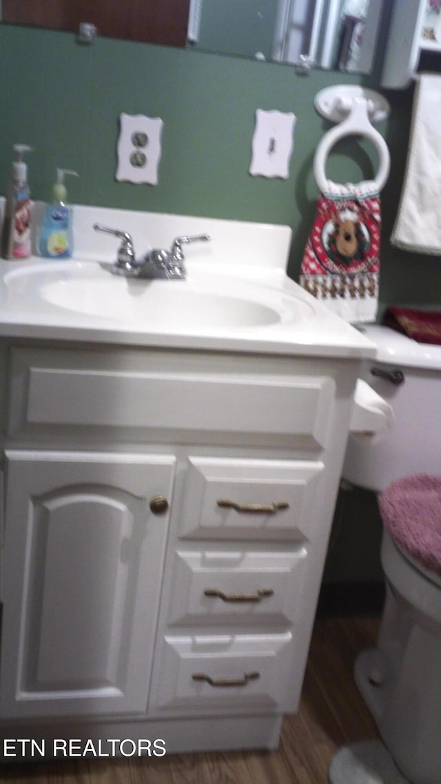 bathroom with hardwood / wood-style floors, vanity, and toilet