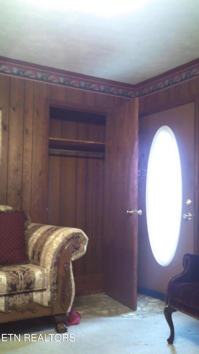 sitting room featuring light colored carpet and wooden walls