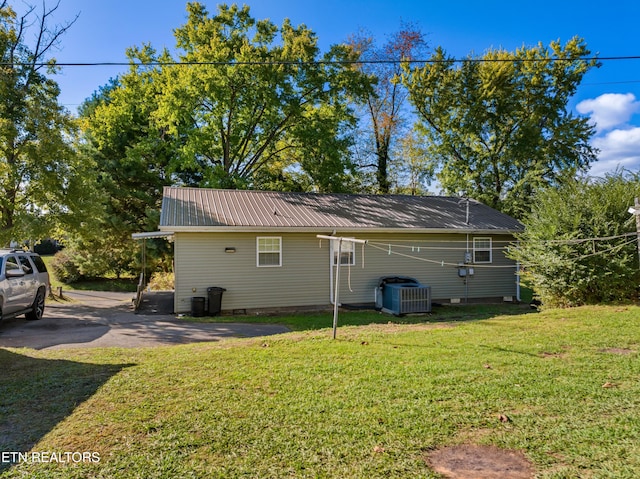 view of property exterior with central AC unit and a lawn